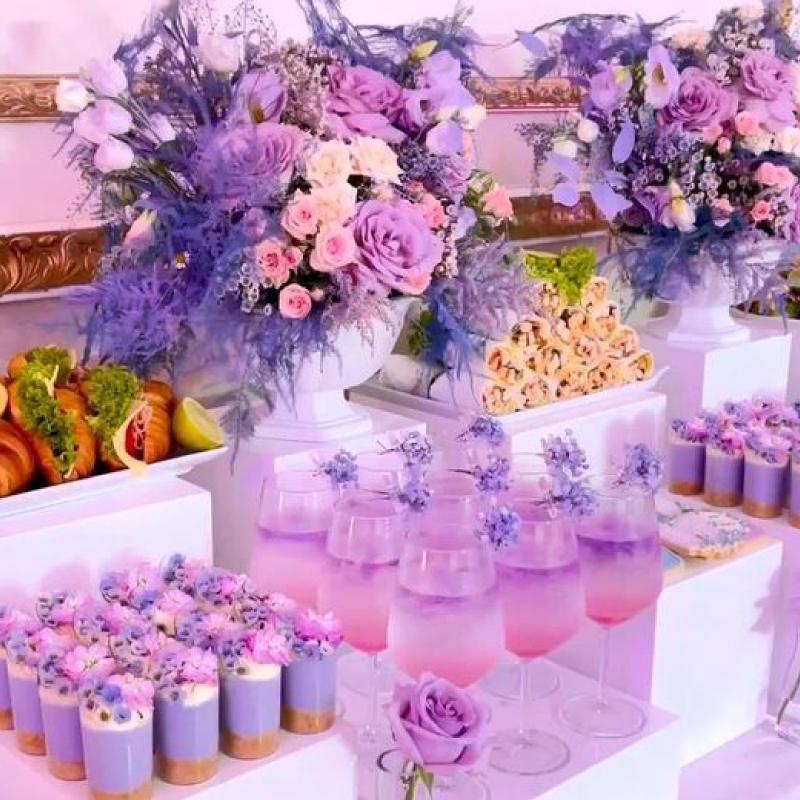 Mesa de dulces y coctelería con decoración floral lila